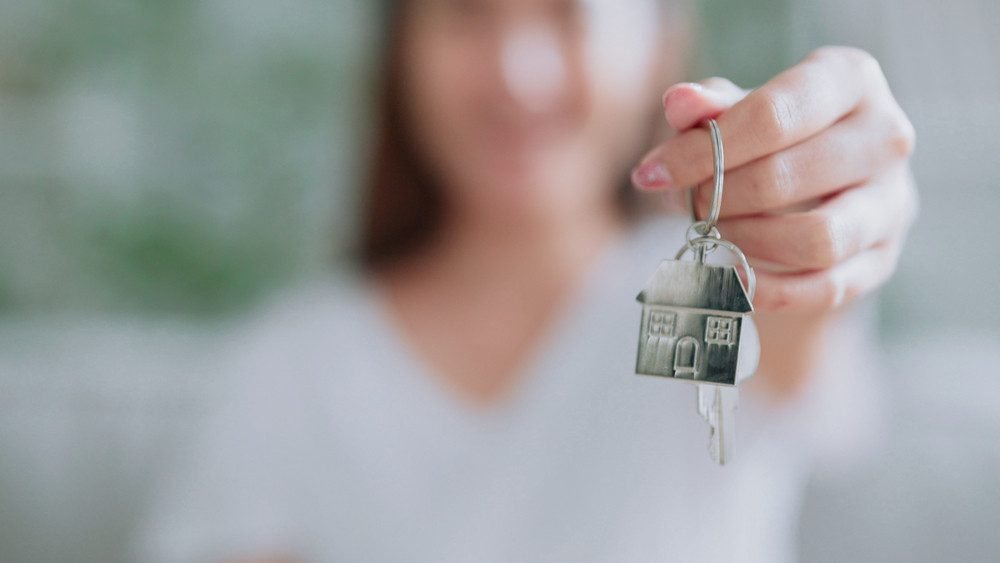 woman holding a keyring of a house