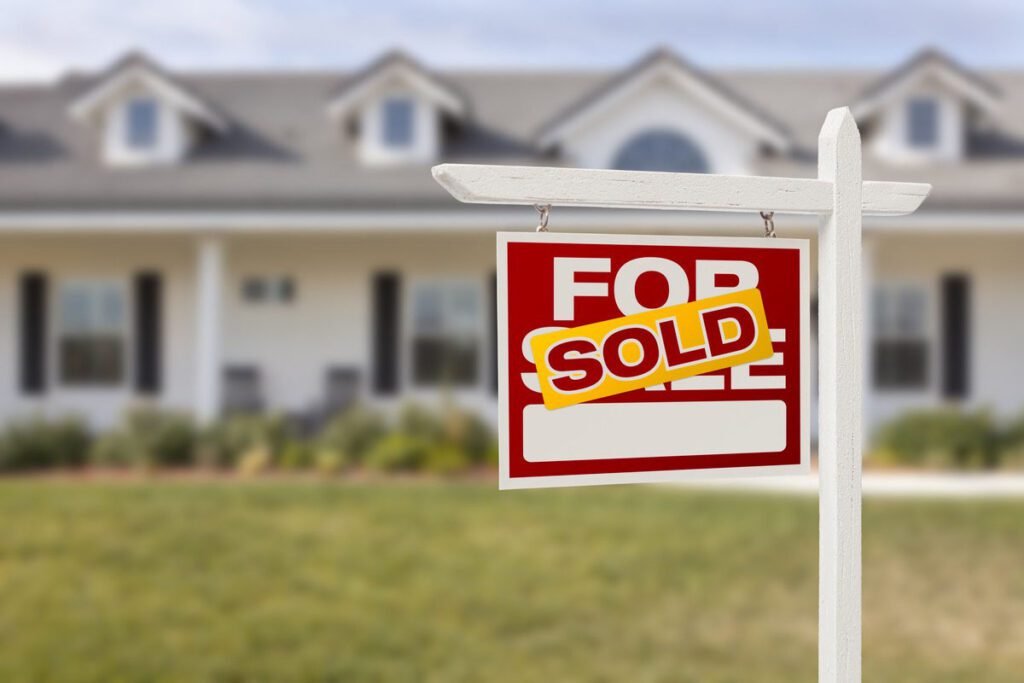 Red sold for sale real estate sign in front of house